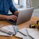 Laptop, próbki płytek, wzornik kolorów i miarka na stole podczas remontu (grafika wygenerowana przez AI)